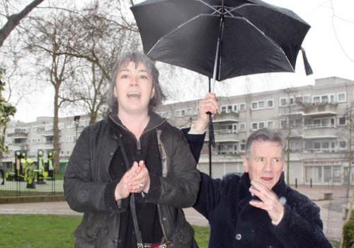 Michael Palin shelters Suza Johnstone from the Gospel Oak rain