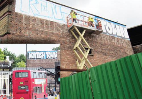 Mr P and his helpers stand on a cherry picker to update the graffiti