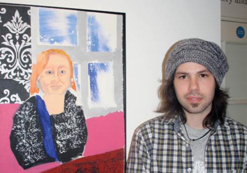 Kaveh Rahimi in front of a self-portrait by Amy Brittan