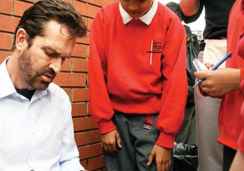 The Hollywood star signs autographs for pupils