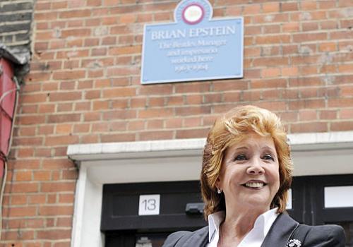 Cilla Black shows off the plaque above Brian Epstein’s first London office