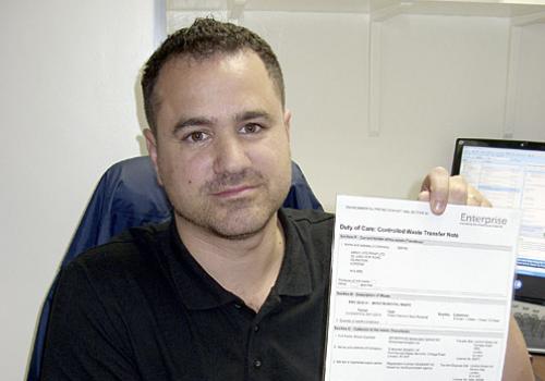 Hak Huseyin with the certificate he displays in his print shop